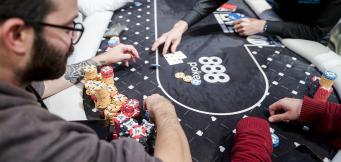 Players competing at an 888poker live table, with chip stacks and cards visible